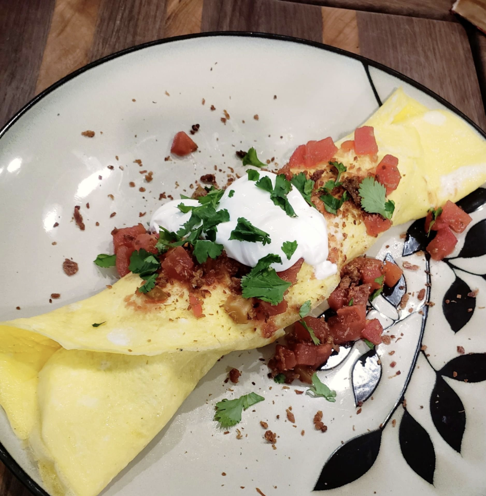 Elegant Southwestern crepe topped with crisp bacon, a dollop of sour cream, and fresh herbs, plated to culinary perfection
