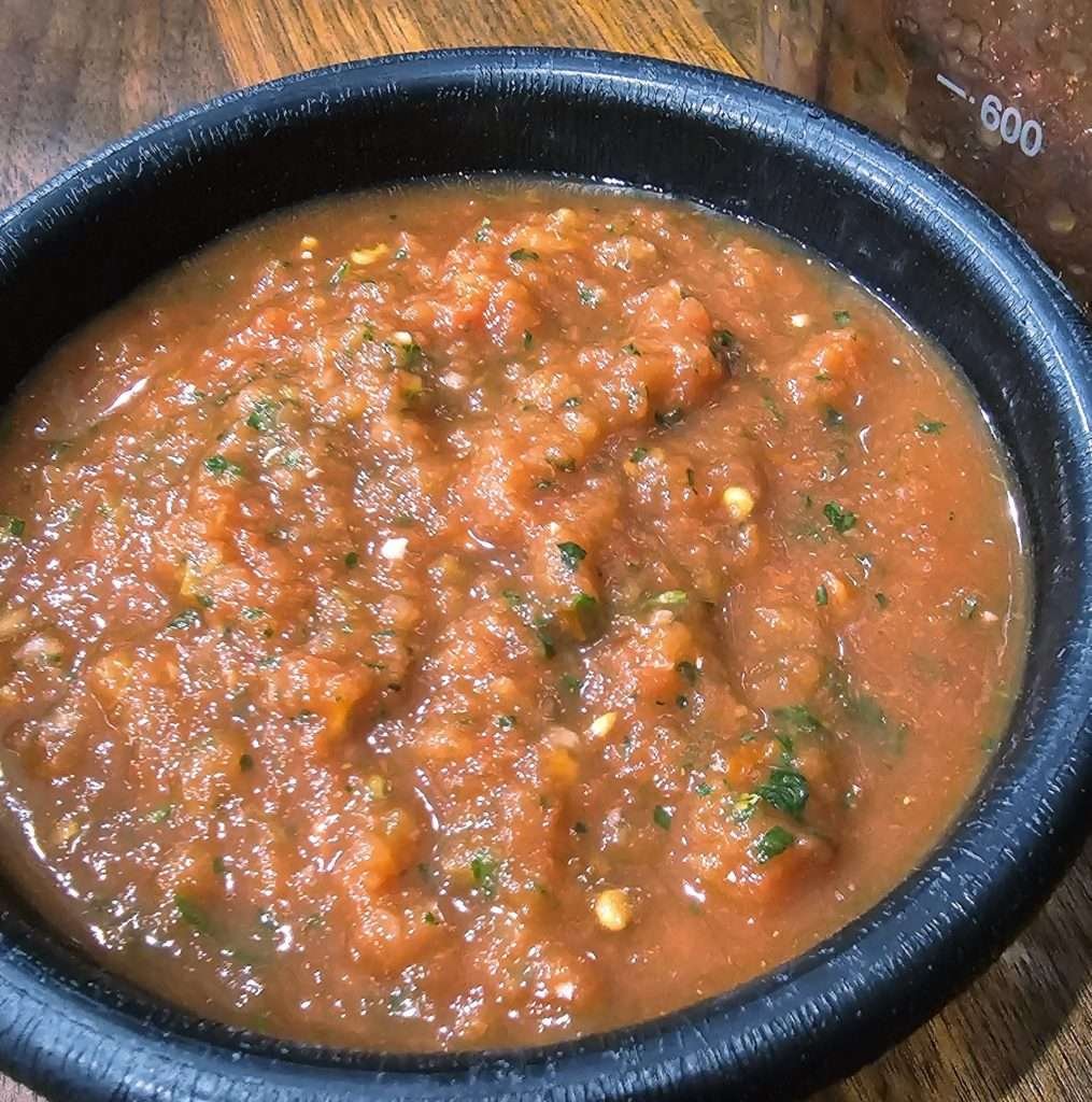 Traditional Mexican-style salsa in a rustic bowl, its rich red hue and chunks of tomato promise a fresh, zesty flavor.