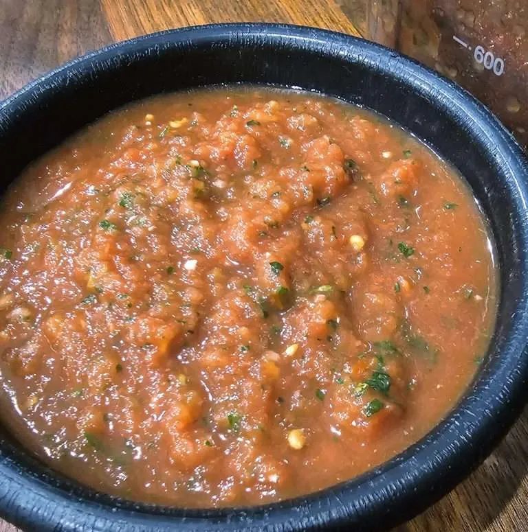 Traditional Mexican-style salsa in a rustic bowl, its rich red hue and chunks of tomato promise a fresh, zesty flavor.
