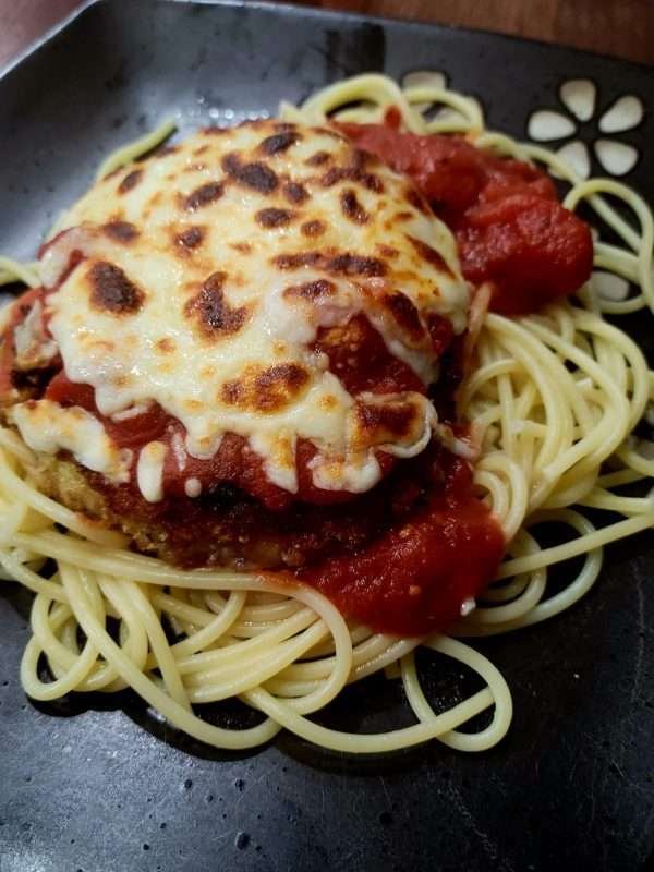 Chicken Parmigiana on a bed of spaghetti, topped with melted mozzarella and tangy tomato sauce, ready to enjoy