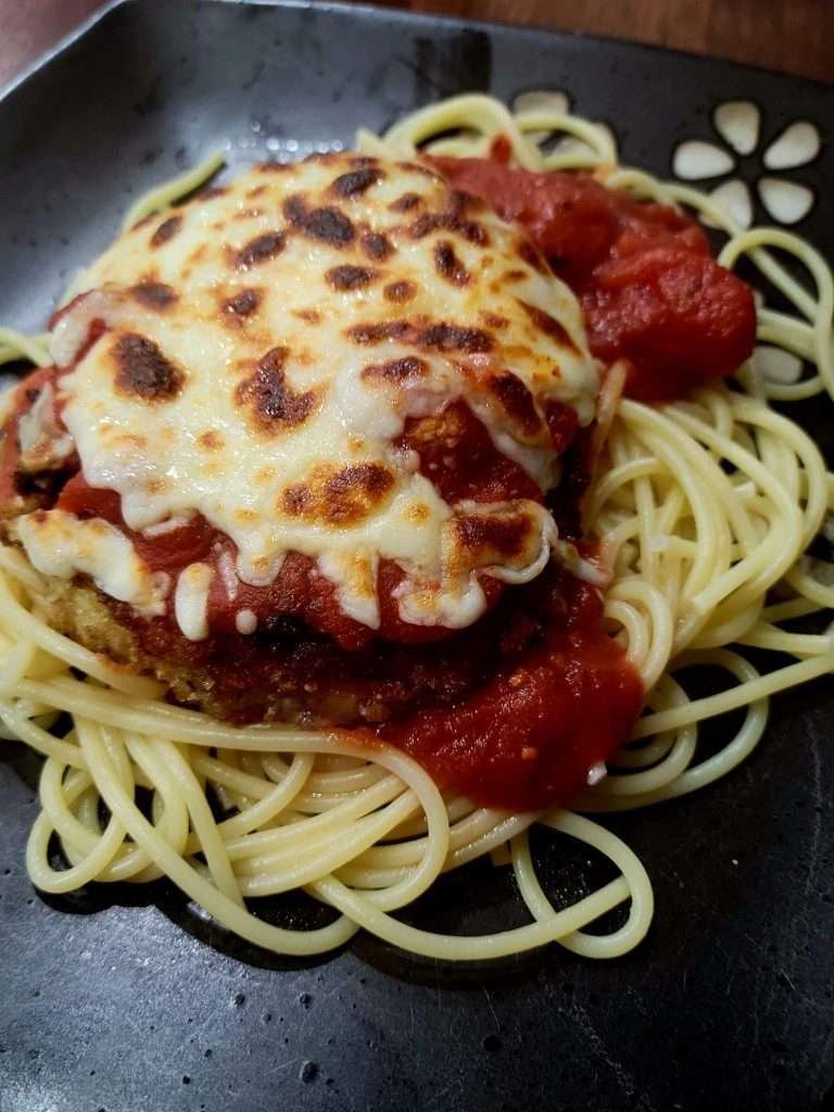 Chicken Parmigiana on a bed of spaghetti, topped with melted mozzarella and tangy tomato sauce, ready to enjoy