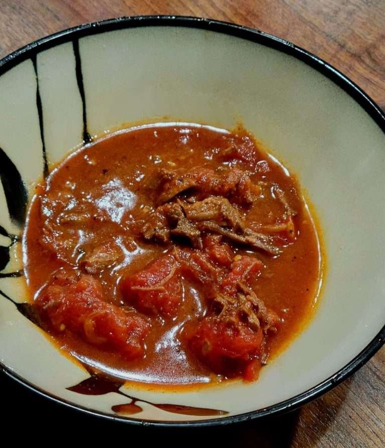 Bowl of rich, award-winning Colorado chili, brimming with tender chunks of meat and hearty tomatoes