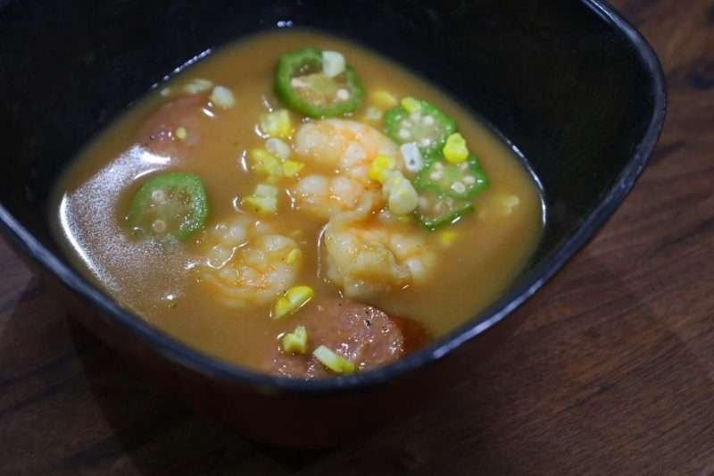 A bowl of spicy shrimp and andouille gumbo with okra and rice, a traditional Louisiana dish steeped in Creole and Cajun flavors